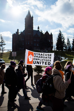 Participants of the protest walk through the campus displaying signs and chanting phrases, like “SU works because we do.” The march proceeded from Carnegie Library to outside the administration offices on the opposite corner of campus. 