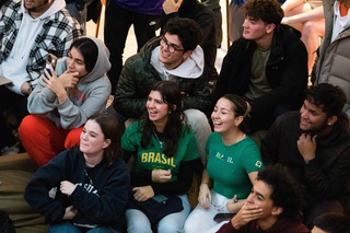 Syracuse freshmen Amanda Salles and Manuela Hees wear their Brazilian clothing with pride as they smile with joy watching the game. The two spent the end of their first semester sharing a moment of cultural pride with their friends. 