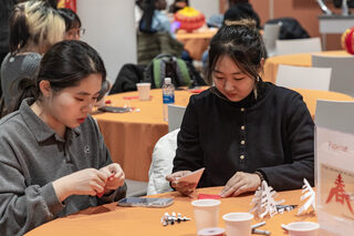 Two students cut folded paper to make three-dimensional versions of the Chinese word “春,” which means Spring. Another name for Lunar New Year is the Spring Festival, so the template to cut out “spring” was displayed on the tables. 