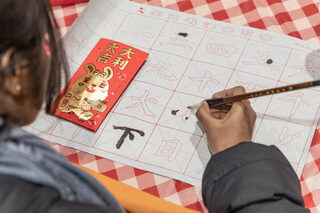 A student draws Chinese characters using tracing paper offered at the event. The tracing paper provides students with little to no experience drawing Chinese characters an opportunity to try their hand at it. 
