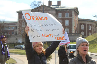 A marcher proudly displays a handmade poster towards the lawn of Crouse-Hinds Hall. SGEU provided pre-made signs at the march to anyone empty handed and wanted a sign.