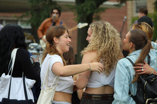 Nancy Dunkle is cheerfully greeted by her friend, Macy Aiken, who roots Dunkle on during her set. The event cultivated a festive tailgate space for both football fans and music enthusiasts to connect on the Quad.