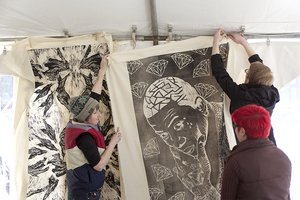 Cayla Lockwood, Tonja Torgerson and Max Moore, two graduate students and a freshman printmaking major, respectively, hang a print relief of Gucci Mane,made by Matthew Kast and Brandon Bridgers, two fourth-year industrial and interaction design majors.