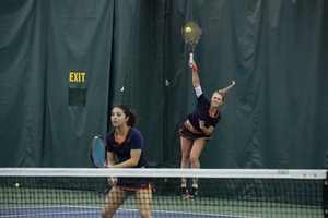 Gabriela Knutson swings at the ball while her partner Miranda Ramirez stands in front of the net. 