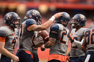 Syracuse players gather with the ball. SU stayed in the game until late in the fourth quarter.